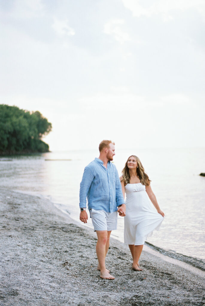 Couple walking barefoot on Edgewater Beach at sunset during Cleveland engagement session.