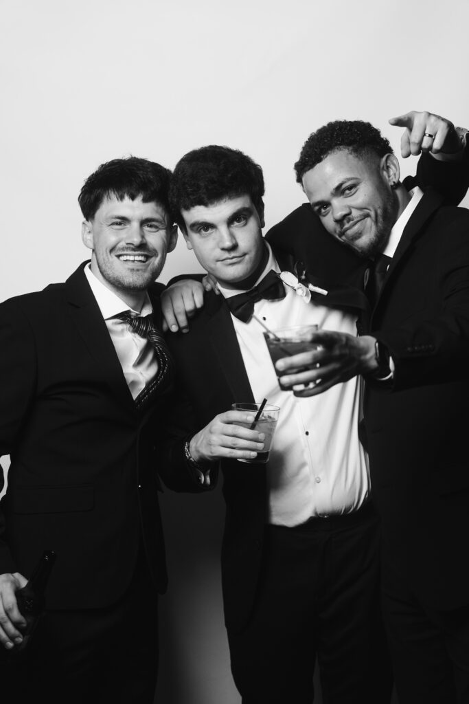Groomsmen toasting with cocktails in black and white guest portrait at Cleveland wedding.